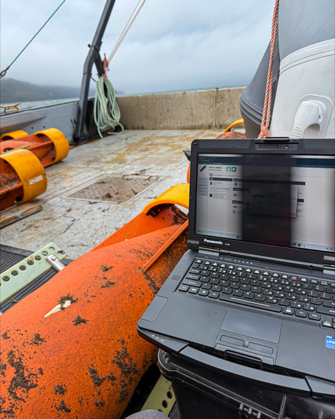 A laptop beside a large orange float from an acoustic mooring.
