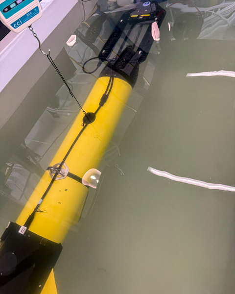 A yellow and black Slocum glider sitting, partly submerged, in a tank.